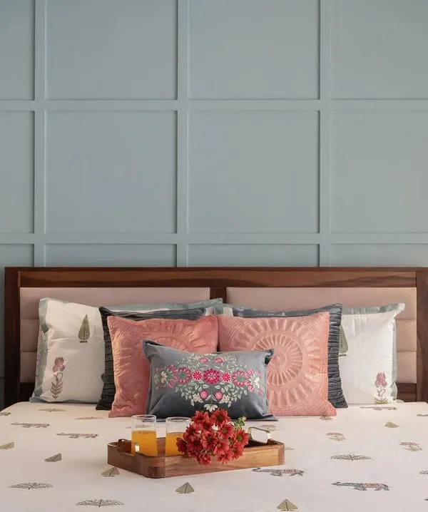 The master bed in this room is set against a beautiful pastel blue wall with classic square paneling. We added small, adjustable reading lights on either side, creating a perfect blend of traditional charm and modern functionality.