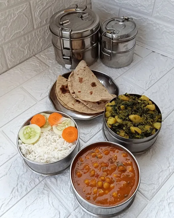 A standard lunch or dinner tiffin, featuring two soft rotis, steamed rice, wholesome aloo methi sabzi, a comforting mutter gravy, and a fresh salad. It's a complete meal designed to be both nutritious and satisfying.