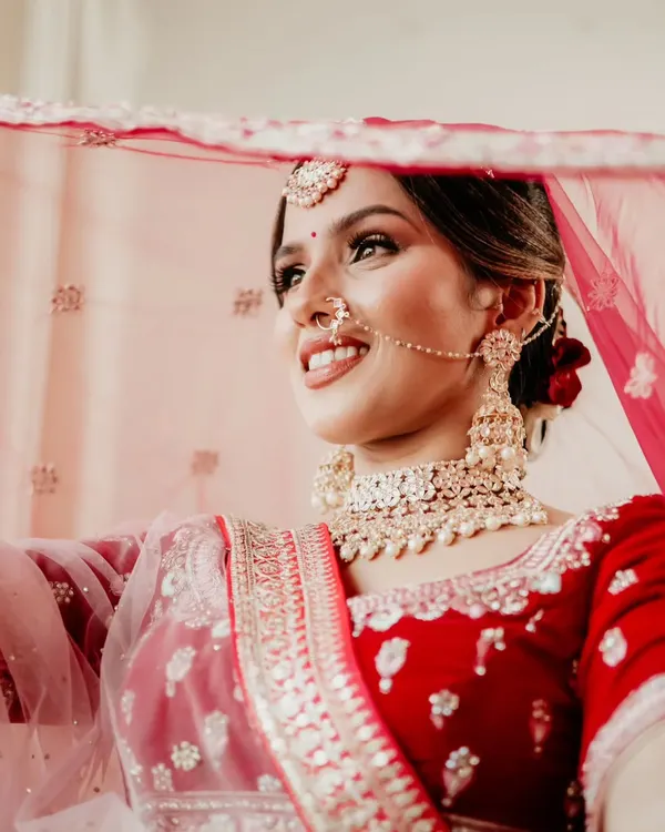 A beautiful, classic bridal portrait. The soft smile and the way she holds her veil create a timeless and elegant image.