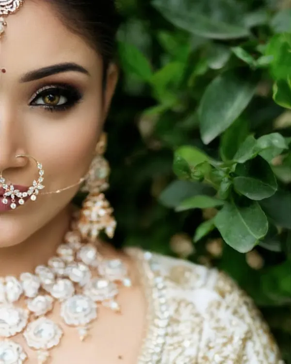 An intense and beautiful close-up of a bride, focusing on her stunning eye makeup and intricate nose ring.