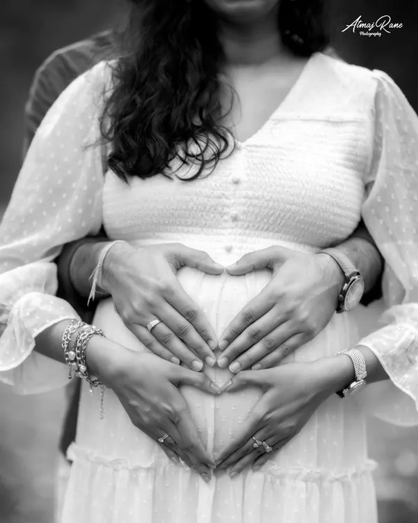 A close-up black and white shot of the parents' hands forming a heart on the baby bump. This iconic pose becomes even more powerful in monochrome, focusing solely on the symbol of love.