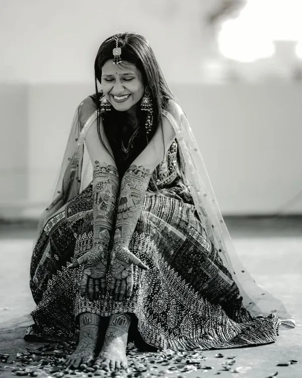 A happy bride, a beautiful design. This black and white shot perfectly captures the joy and elegance of the mehndi ceremony.