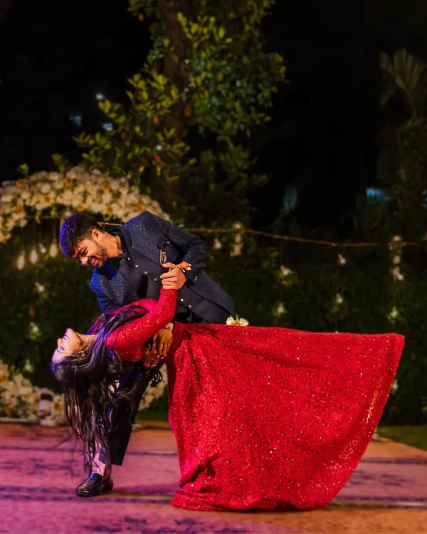 The couple shares a romantic dance, with the groom dipping the bride in her stunning red gown. This is a perfect, movie-like moment from their reception.