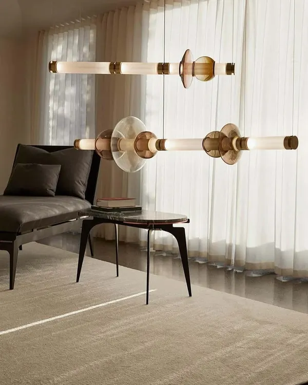 The Luna series by Gabriel Scott, configured as two horizontal pendants. The design stacks various blown glass shapes onto a linear frame, referencing the moon's diffused light and soft glow.