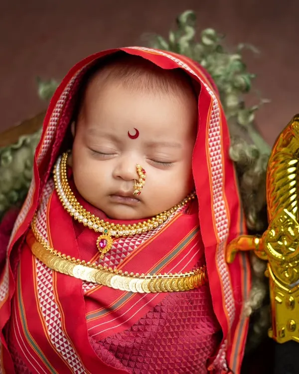 A beautiful portrait of a newborn as Rajmata Jijabai, complete with a traditional red saree wrap, gold coin necklace, and a miniature sword. I focus on getting these details just right while the baby sleeps soundly.