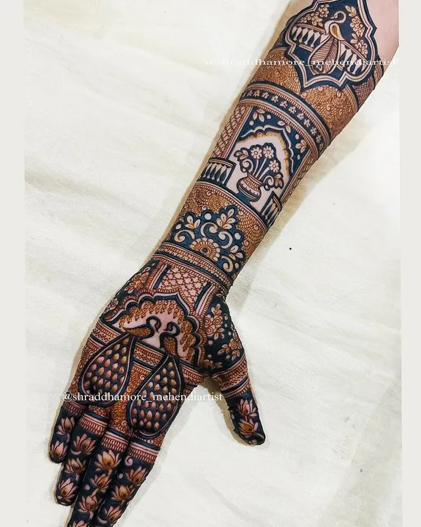 A celebration of peacocks. This design features pairs of peacocks on the palm, symbolizing love and beauty, with a traditional kalash on the arm for prosperity.