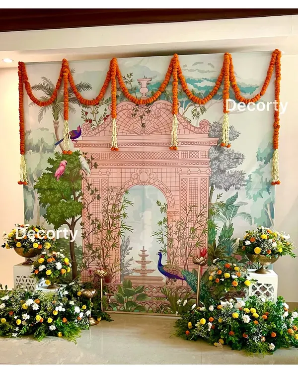 A stunning Pichwai art backdrop for a Mundan ceremony. The traditional Indian artwork is complemented by marigold garlands and lush floral arrangements, creating a beautiful blend of art and nature.