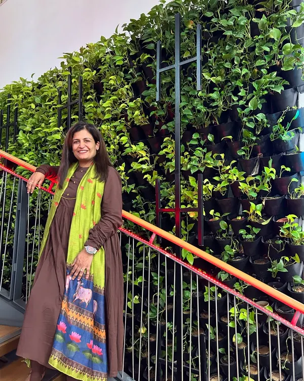 I'm standing proudly next to our "Narcissus Project," a living vertical garden installed along a staircase. This wall of lush pothos plants brings so much life and fresh air to the space, turning a simple stairwell into a beautiful experience.