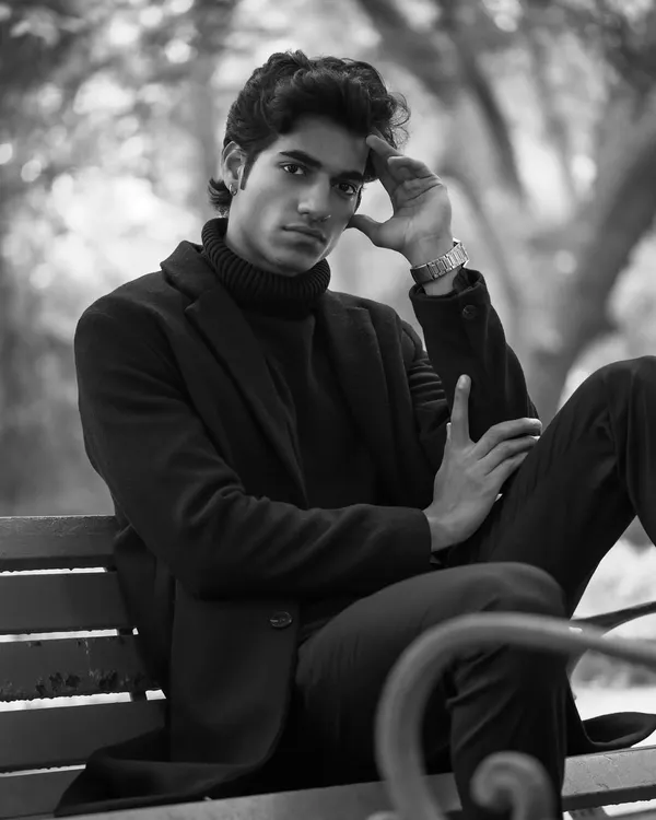 This black and white portrait, taken on a park bench, has a thoughtful and cinematic feel. The monochrome treatment emphasizes the texture of the clothing and the model's contemplative expression.
