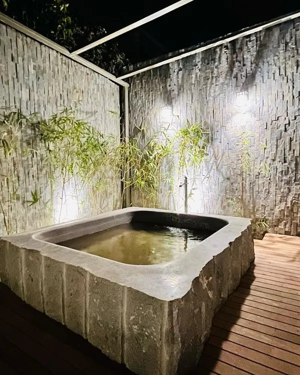 We specialize in creating serene, Zen-inspired spaces. This custom-built Japanese stone bath, set against textured stone walls and bamboo, provides a private, tranquil retreat. We manage all aspects, from sourcing the natural stone to the plumbing and lighting installation.