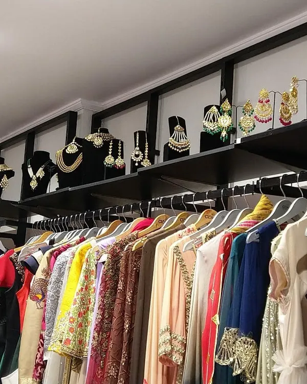 Our store is a treasure trove of designer wear, with racks organized to help you browse easily. You can also see our collection of statement jewelry displayed above, perfect for completing your look.