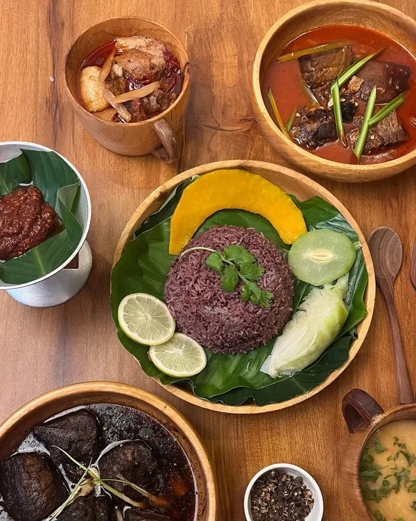 A classic Naga thali, showcasing a balanced meal. It includes purple sticky rice, Anishi smoked pork, pork with bamboo shoot, a fiery chutney, boiled vegetables, and dal.