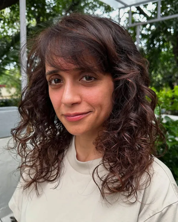Curly and proud. I gave her curls a new life with a fresh cut, including a fringe, and subtle reddish-brown highlights to define the texture. Embracing your natural curls is always a good idea.