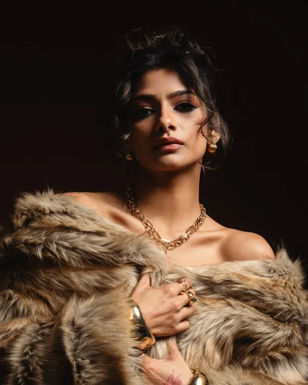 A powerful editorial shot featuring a bold, winged smokey eye. The combination of the intense makeup, messy updo, and luxurious fur coat creates a high-fashion statement.