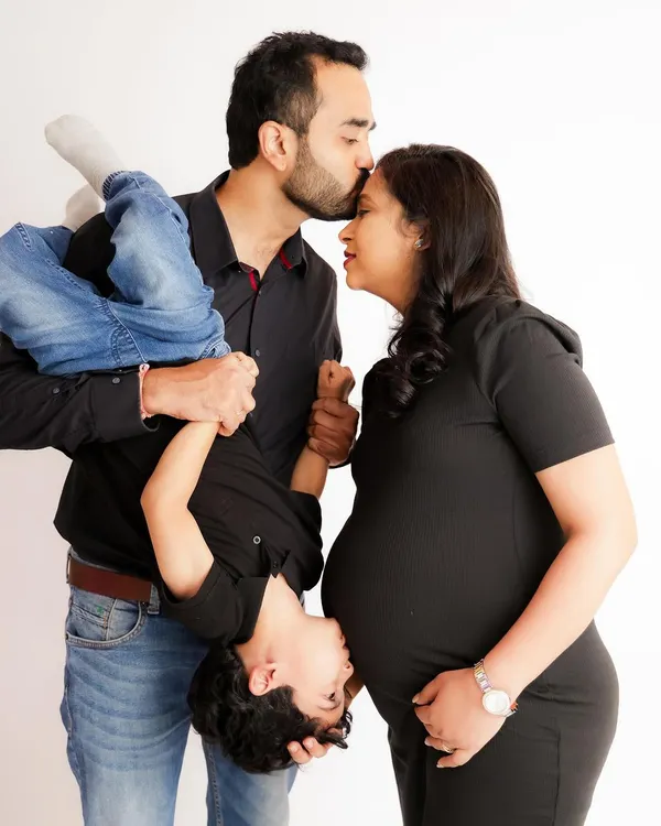 A playful and heartwarming family portrait. This photo perfectly captures the fun and chaos of family life as the parents-to-be share a laugh with their energetic son.