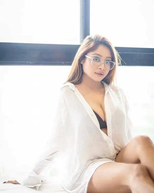 A soft, naturally lit portrait of a model in a simple white shirt. The glasses add a touch of character, creating a relatable and stylish lifestyle image.