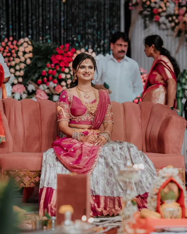 A client looking beautiful at her event in a custom Langa Dhawani, featuring a grey and maroon skirt paired with a pink embroidered blouse.