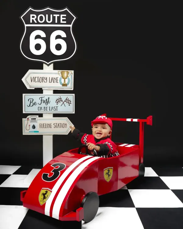 Ready, set, go! This little racer is all smiles in our custom Route 66 setup, complete with a Ferrari-inspired car and checkered floor. It's a high-energy theme perfect for an adventurous toddler.
