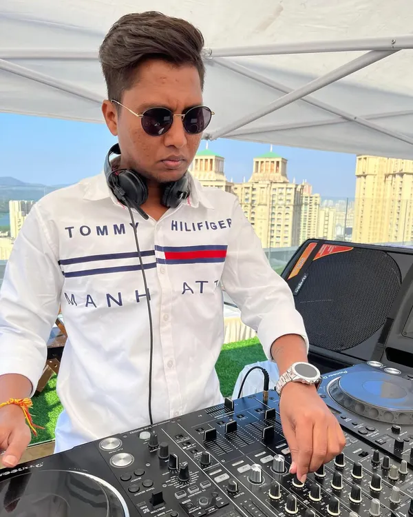 A daytime rooftop gig with the city skyline as my backdrop. I'm focused on the mix, using my Pioneer DJ setup to craft the perfect sound.