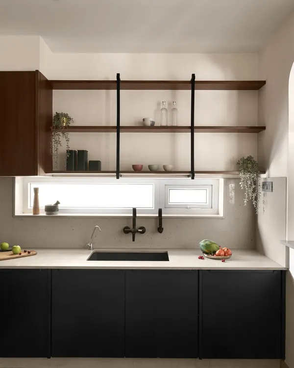 This kitchen renovation features a clean, modern design with black lower cabinets and open wooden shelves. A wide window above the sink floods the space with natural light, making it feel bright and airy.