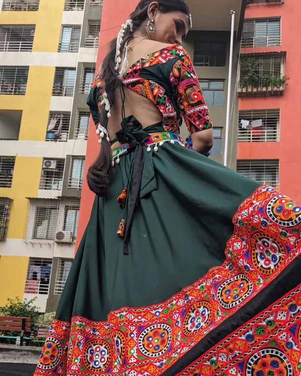 Our Garba night lehengas have a full, wide flare perfect for twirling. This green chaniya choli with a colorful border is available to rent, with jewelry options too.