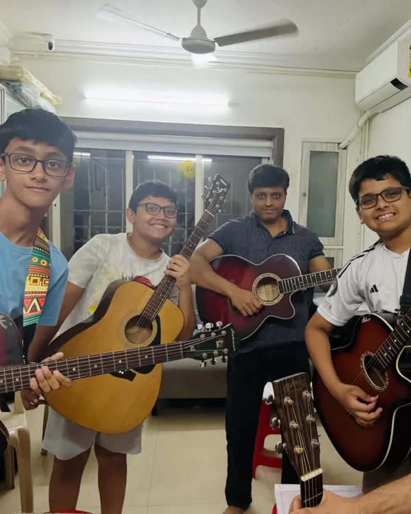 There's nothing like the energy of a group guitar class. Here, our students and a coach share a moment of camaraderie after a productive session, each holding their instrument with pride.