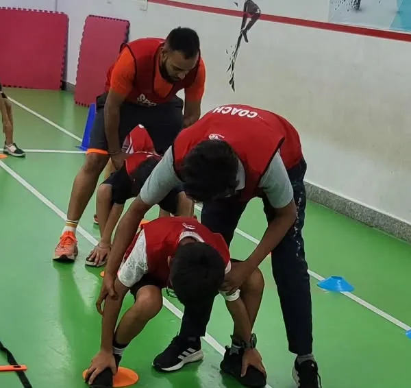 Our coaches are always on hand to provide personalized feedback and adjustments. Here, a coach helps a young athlete perfect their form during a drill, ensuring they perform the movement correctly and safely.