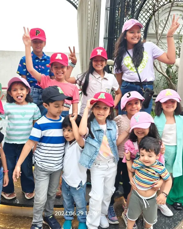 A large group of happy kids posing together in their custom initial caps after a fun party activity. This is the kind of group fun and memorable favor our live station creates.