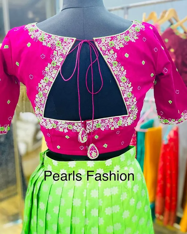 A bright pink blouse with a triangular keyhole back design. The cutout is framed with neat floral embroidery, and the tie-up has matching fabric latkans.