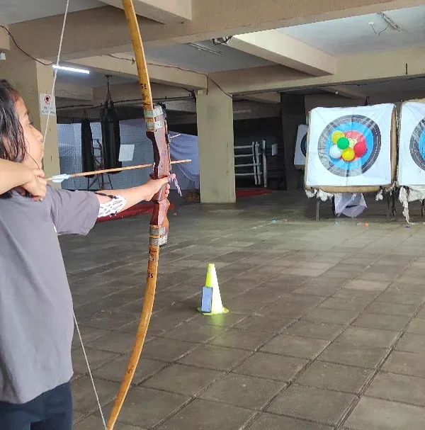 A young archer takes aim with great concentration. Learning to block out distractions is a key mental skill we practice.