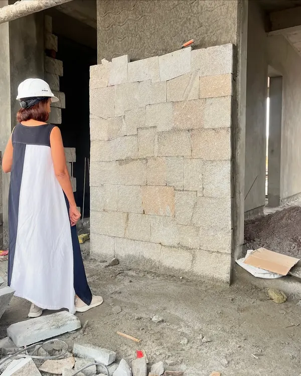 Our process is deeply hands-on. Here, we are on-site inspecting a mock-up wall of hand-cut stone, ensuring the texture, color, and jointing meet our exact specifications before full-scale construction begins. This attention to detail is what makes our work special.