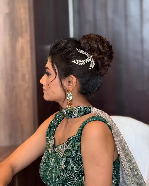 A chic and messy high bun, perfect for a reception or cocktail party. The delicate silver accessory adds a touch of modern elegance.