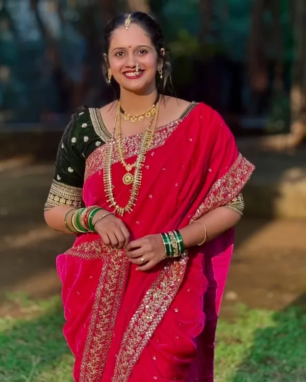 A beautiful close-up of a client wearing the pink velvet Nauvari saree, complete with traditional jewelry like the nath and layered necklaces. Her smile says it all.