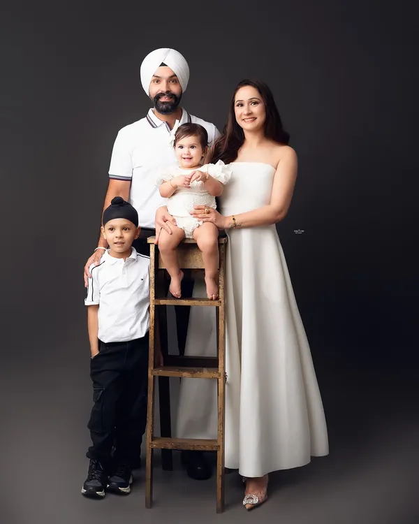A picture of modern elegance. This family's coordinated black and white outfits create a sharp, stylish look against the dark grey backdrop, resulting in a sophisticated family portrait.