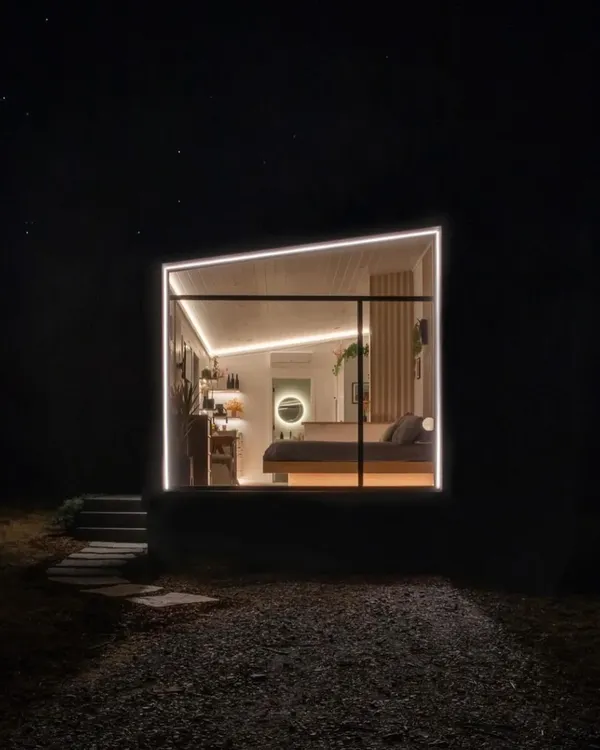 A beautifully lit modular living space at night. The combination of large windows and strategic LED lighting creates a warm, inviting ambiance, showcasing the home's modern design.