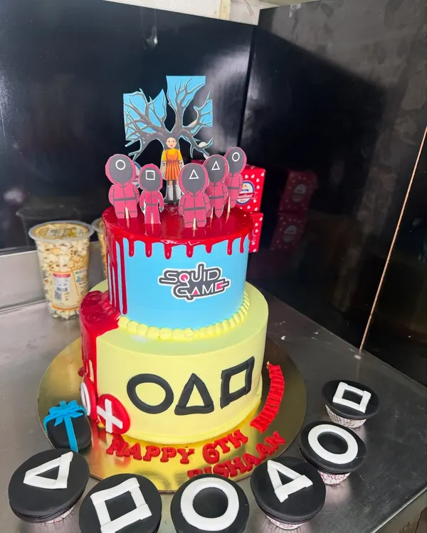 Red light, green light, time for cake! This two-tier Squid Game themed cake was a huge hit for a 6th birthday party. It features iconic symbols from the show and even comes with matching cupcakes, showing how we can bring any pop culture theme to life.