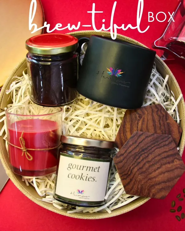 Our "Brew-tiful Box" is the perfect gift for any coffee aficionado. This curated hamper includes gourmet coffee, a custom-branded mug, artisanal cookies, elegant wooden coasters, and a scented candle to create a complete sensory experience.