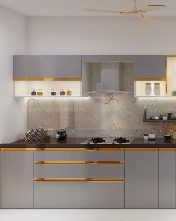 This modern kitchen design features warm grey cabinets with sleek gold-toned handles. The under-cabinet lighting beautifully illuminates the marble backsplash, creating a space that is both functional and luxurious.