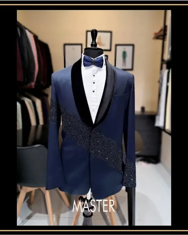 A closer look at this navy blue tuxedo, featuring a velvet shawl lapel and a diagonal spray of crystal work. This is a designer tuxedo for a groom who wants a touch of modern bling.