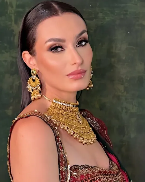 This is a classic bridal look created for a jewelry campaign. The makeup is defined and elegant, with a sharp winged liner and warm tones to complement the heavy gold jewelry and traditional red and green lehenga.