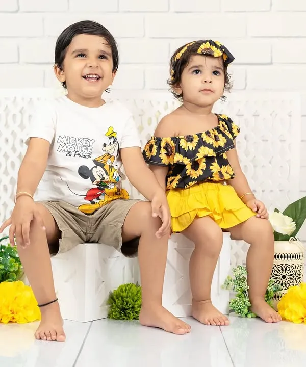 A charming portrait of a brother and sister sitting together. Their coordinated yellow and black outfits are stylish and fun for a kids' photoshoot.