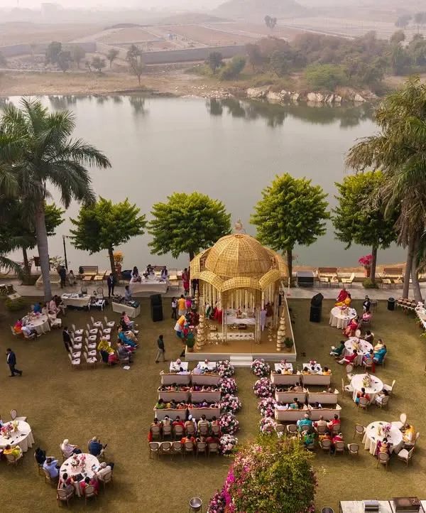 An aerial view of a breathtaking lakeside wedding ceremony at Shikarbadi Hotel, Udaipur. I designed this golden-domed mandap to be the focal point, perfectly positioned to capture the serene beauty of the natural landscape.