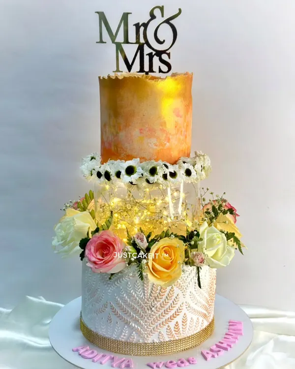 A beautiful wedding cake with a modern twist. I used a cake spacer with fairy lights to create a magical floating effect between the tiers, complemented by fresh flowers.
