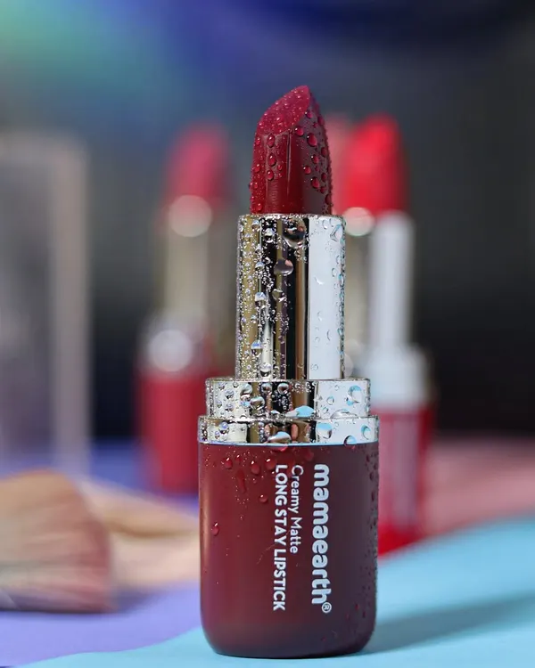 A close-up of a Mamaearth matte lipstick, covered in fine water droplets, to emphasize its rich color and hydrating quality against a soft, dreamy background.