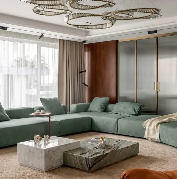 This living room captures our signature style of quiet luxury. We used a palette of muted sage green and warm neutrals, combining plush fabrics with natural stone and marble coffee tables. The design is elevated by brushed gold accents and floor-to-ceiling marble panels, creating a space that feels both sophisticated and inviting.