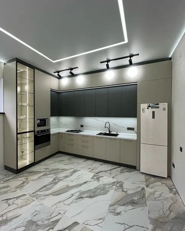 This modern L-shaped kitchen combines style and function. I used a two-tone scheme with sleek, handle-less cabinets, integrated appliances, and a stunning marble-patterned floor. The design includes a glass-fronted display cabinet with internal lighting to showcase crockery, alongside track and recessed ceiling lights for a bright, inviting atmosphere.