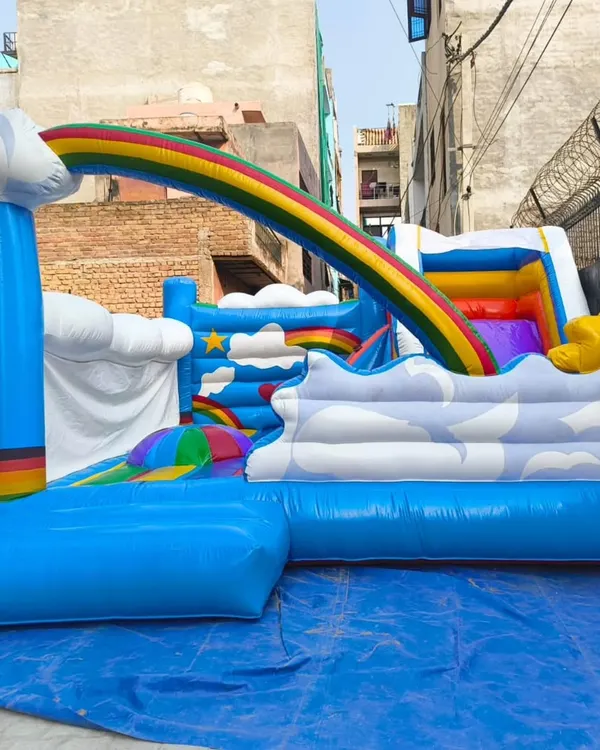 A unique rainbow and clouds-themed bouncy. This model features a slide that goes over a rainbow arch into a cloudy play area.