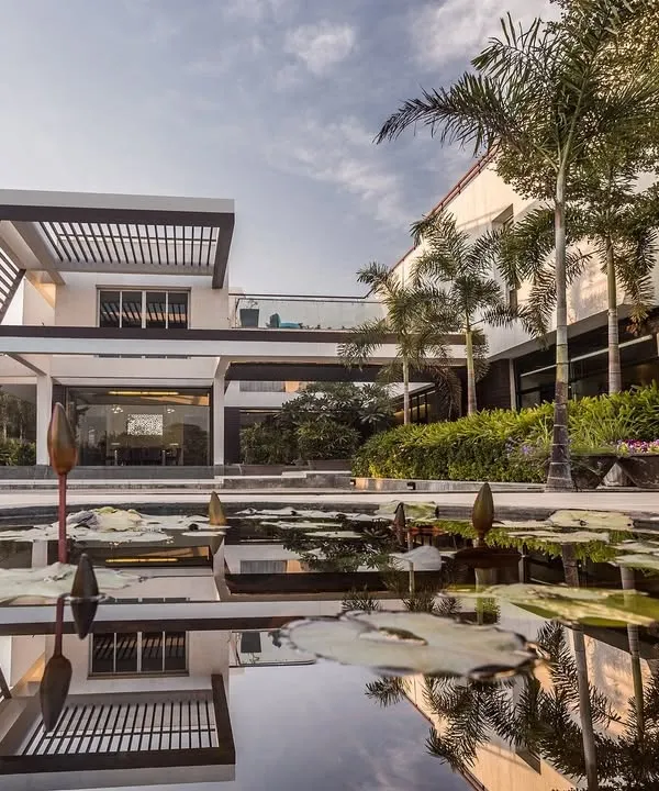 Our Abhyudaya villa in Ahmedabad exemplifies climate-responsive modernism. The design features a floating white mass with scooped hollows to create dynamism, while a central courtyard and a surrounding water body establish a comfortable micro-climate, seamlessly integrating the home with its environment.