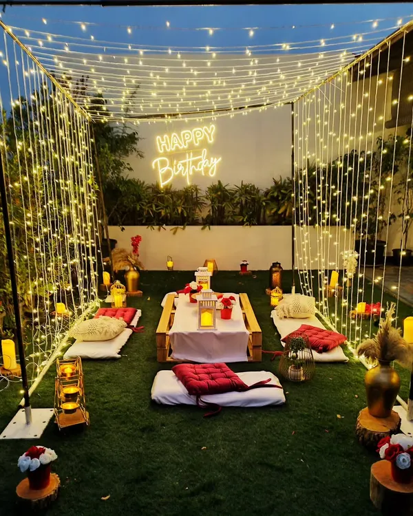 A magical "cabana of lights" created for a birthday celebration. The structure is formed entirely by curtains of warm string lights, enclosing a low picnic table for a brilliantly lit and intimate dining experience.