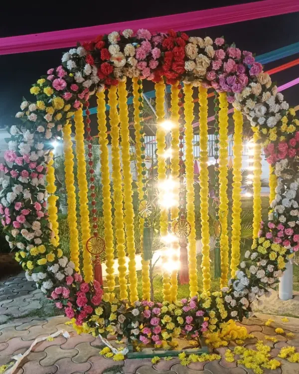 A circular floral frame is a popular choice for outdoor Haldi and Mehendi events. Here, I created a large ring with colorful flowers and hanging marigold strings, which looks fantastic in night-time photos.